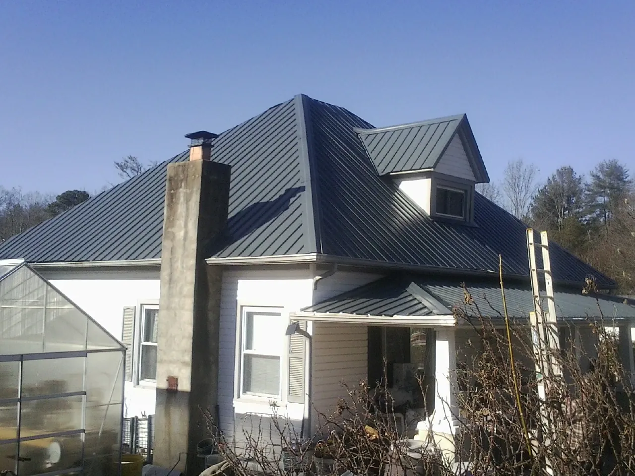 Dark blue standing seam metal roof on a white farmhouse with dormer — Slate & Tile Roof Repair by Roofing Brothers in Peckville