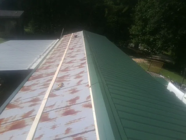 Old rusted panels beside newly installed green metal roofing — Wind Damage Roof Repair by Roofing Brothers in Peckville