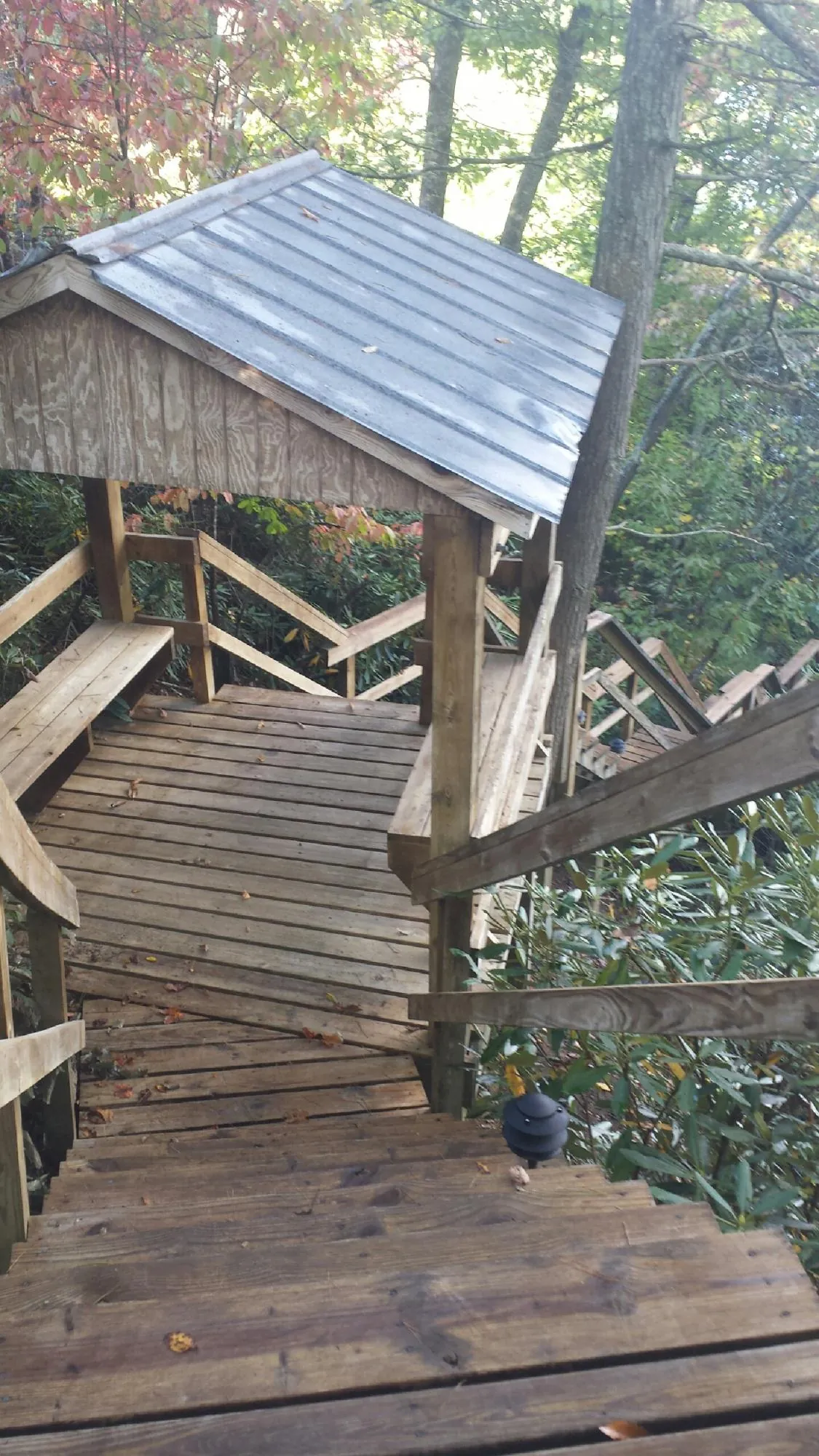 Metal roofed shelter over wooden steps on a wooded walkway — Skylight Repair & Installation work by our crew in Peckville