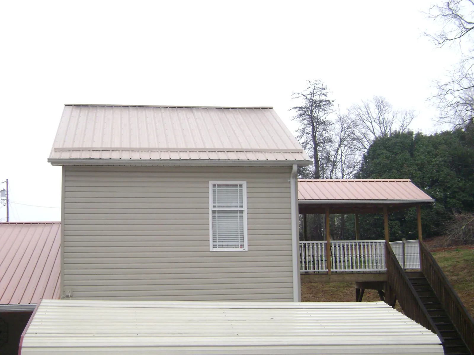Tan metal roofs on a two story addition and attached porch, from a Roof Replacement job in Peckville