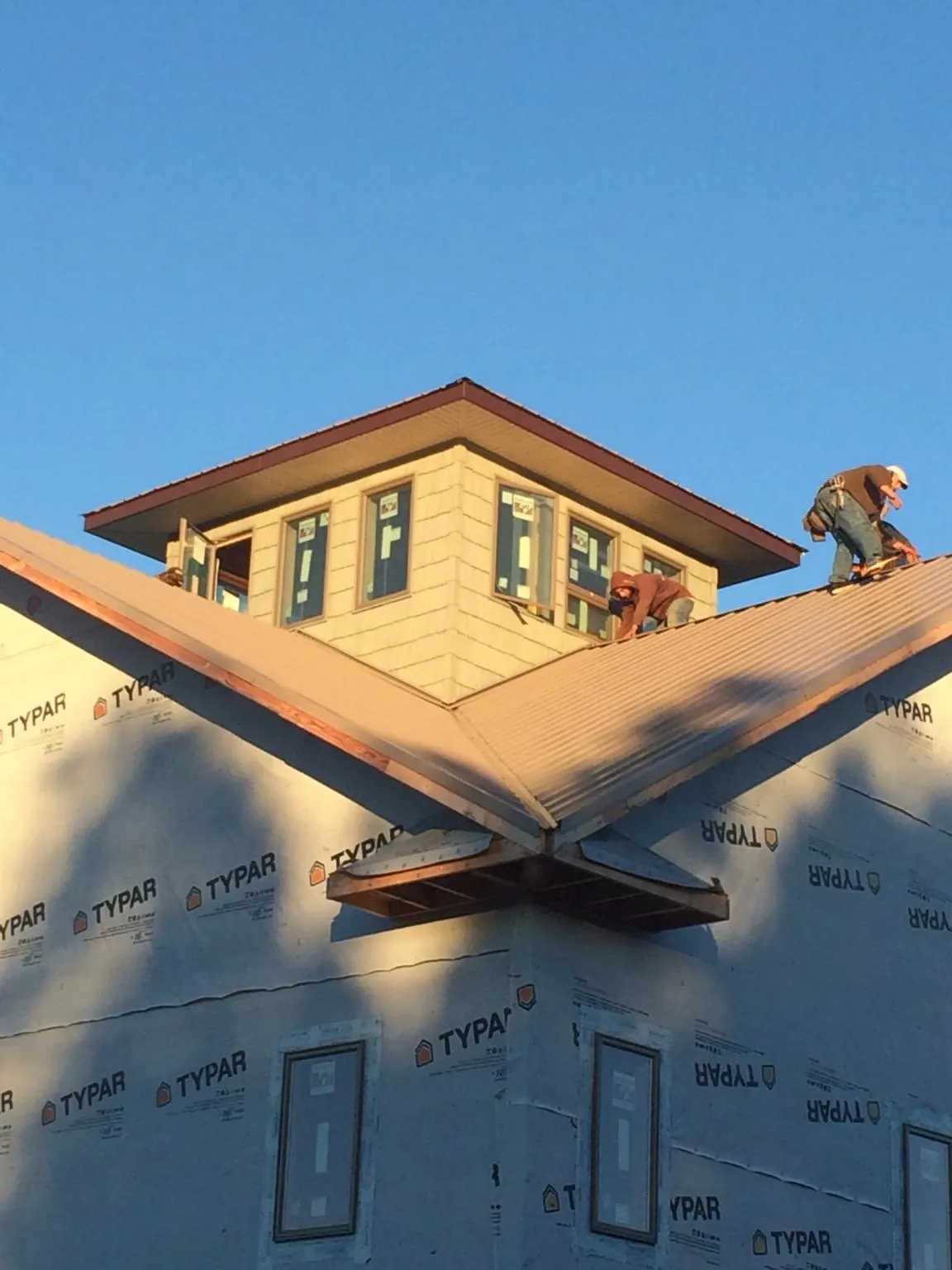 Roofers working around a rooftop cupola on a new metal roof at sunset — Roof Waterproofing in Peckville by Roofing Brothers